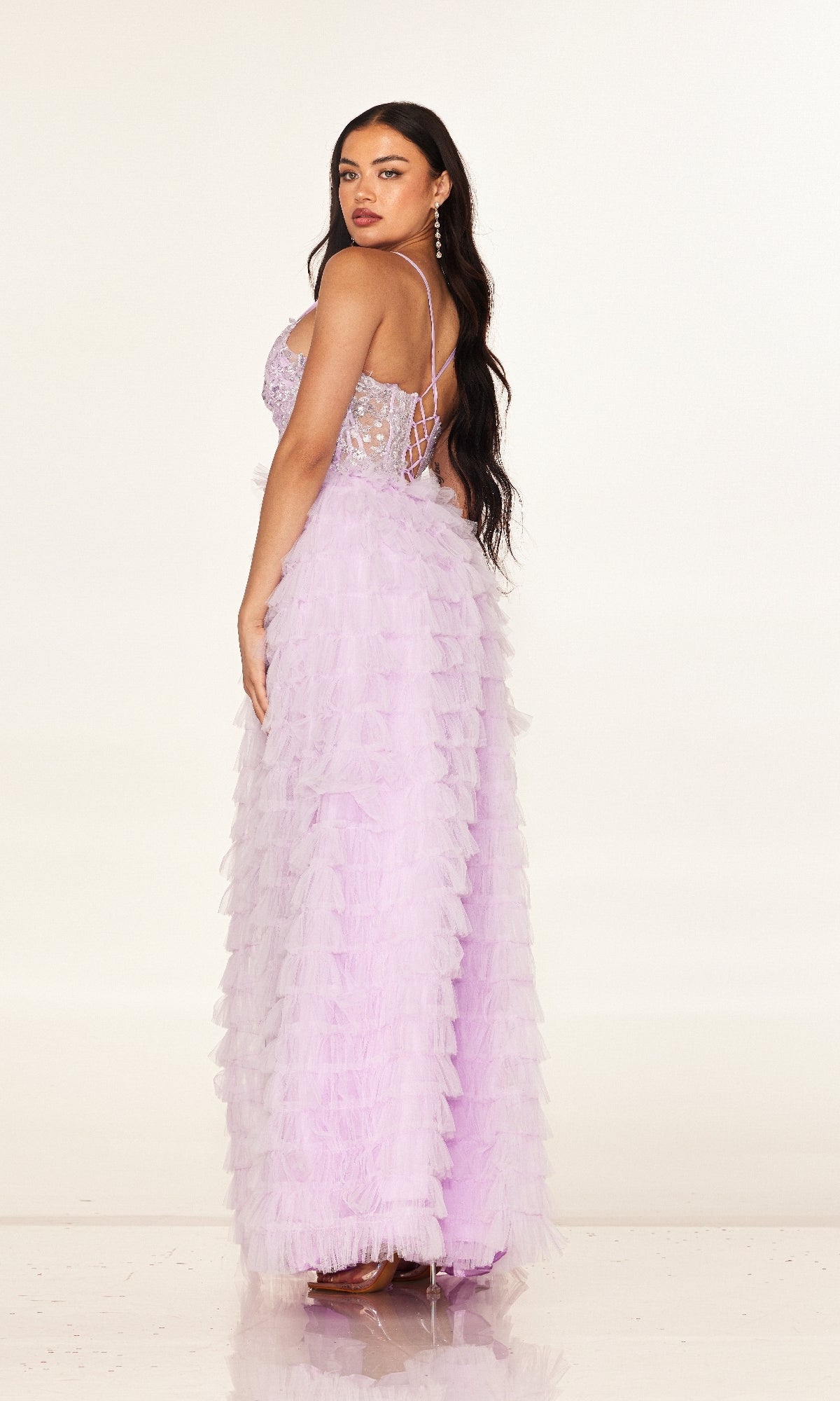 A woman wears the Cecilia Couture 2624 long prom dress, featuring a light purple A-line silhouette with a sheer corset bodice and lace-up back, standing and looking over her shoulder.